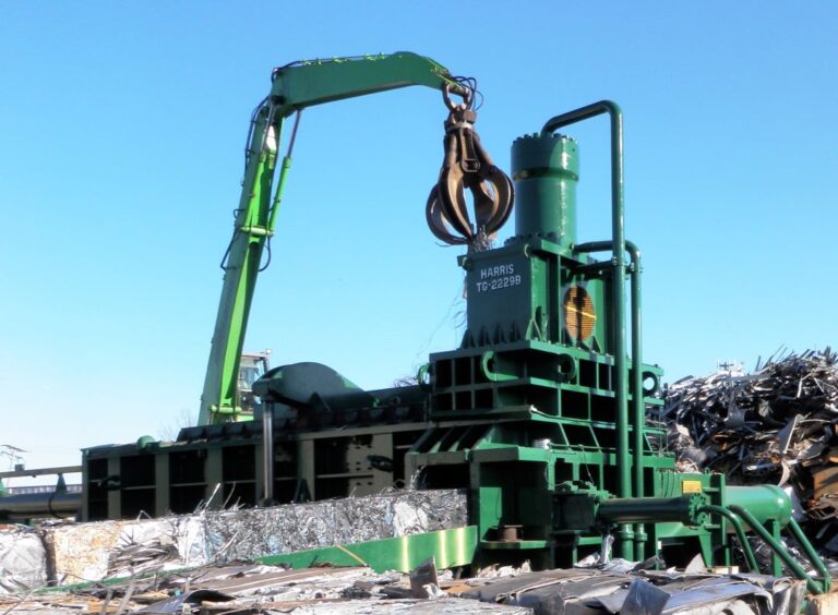 Green Crane Machinery sorting non ferrous and ferrous metals in a scrap yard.